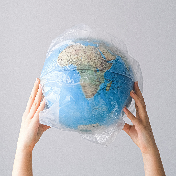 hands holding globe wrapped in plastic